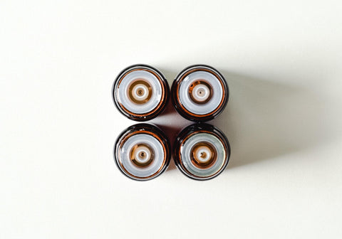 Top view of four amber glass bottles with dropper caps in